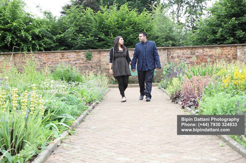 HAPPY COUPLE WALKING HAND IN HAND IN PARK WITH PROPOSAL PHOTOGRAPHER LONDON TAKING PHOTOS OF THIS SPECIAL MOMENT